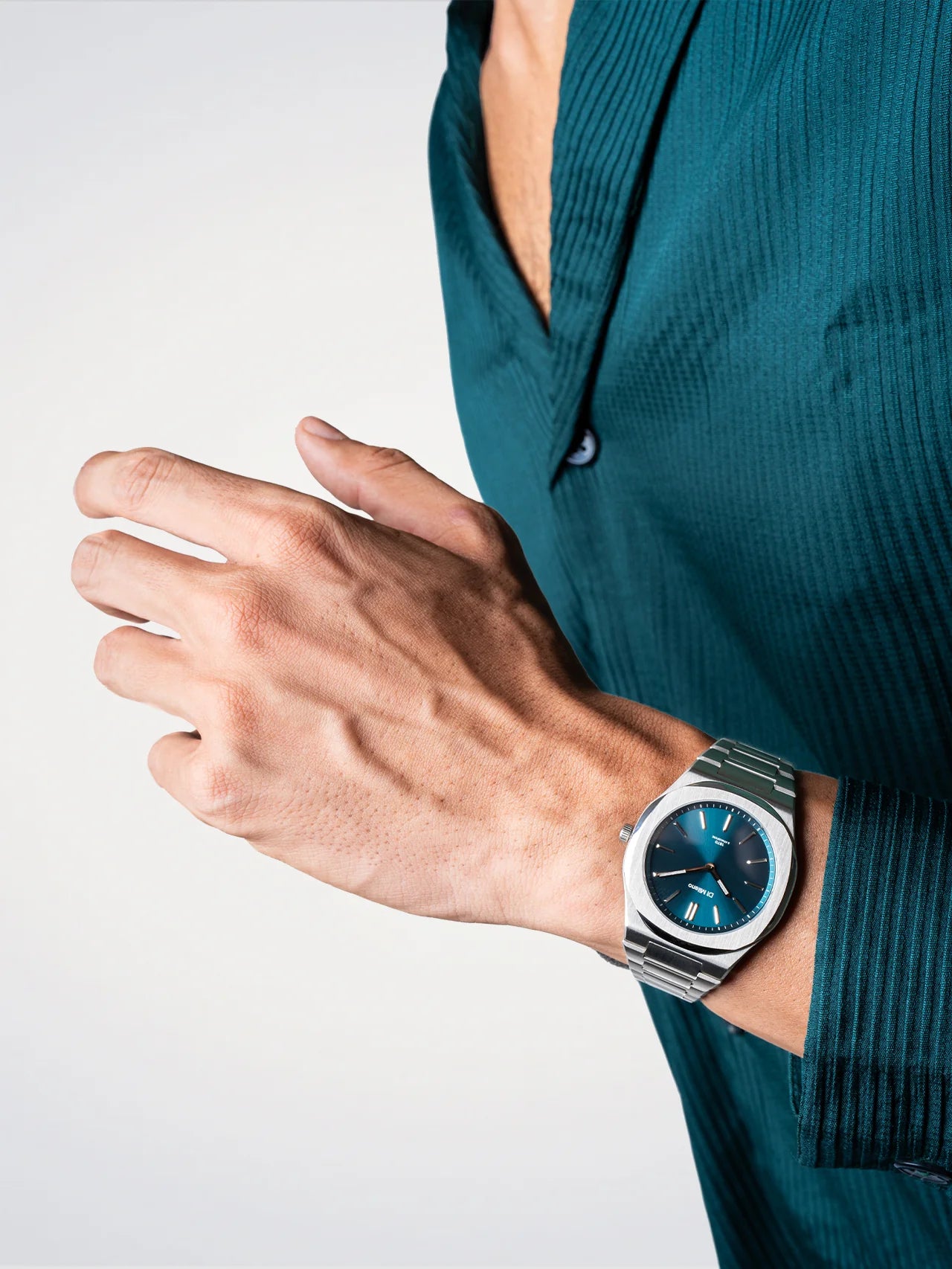 Hand wearing a silver watch with a blue face on a white background
Salam Luxury