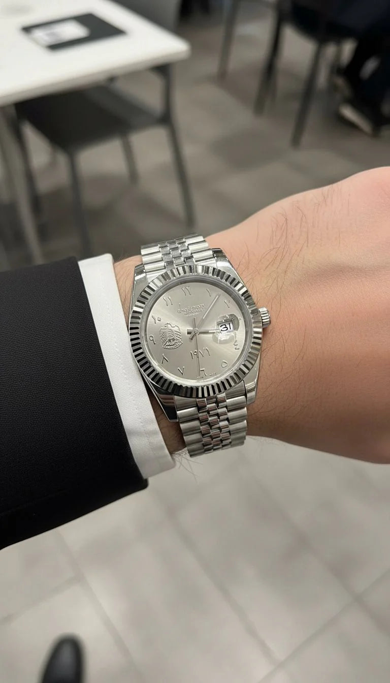 Silver watch on a person's wrist with a blurred indoor background
Salam Luxury