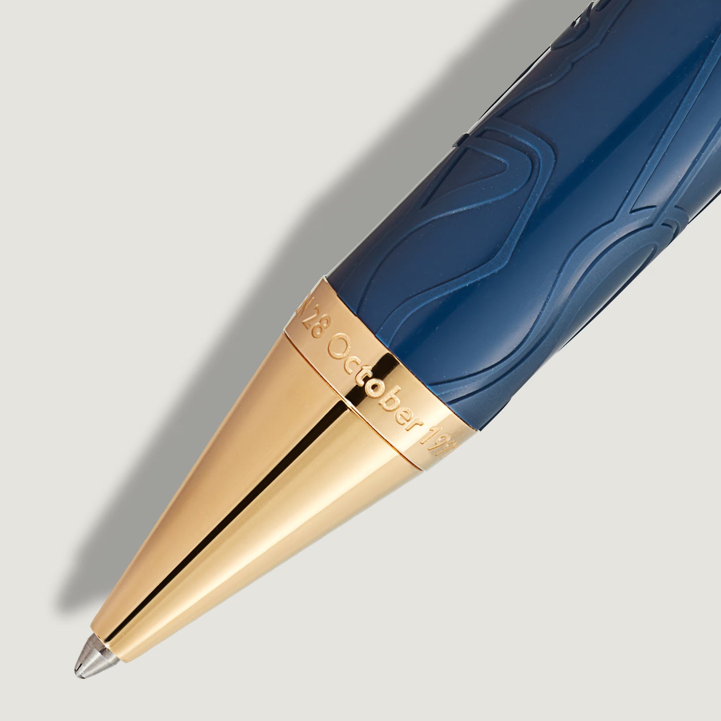 Extreme close-up of the champagne gold-coated tip with date engraving and royal blue patterned barrel of Montblanc Queen Victoria ballpoint pen from Salam Luxury.