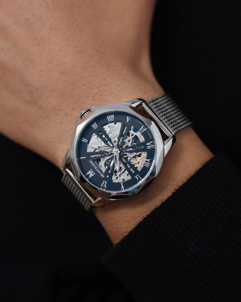 Silver watch with a blue face on a wrist against a dark background