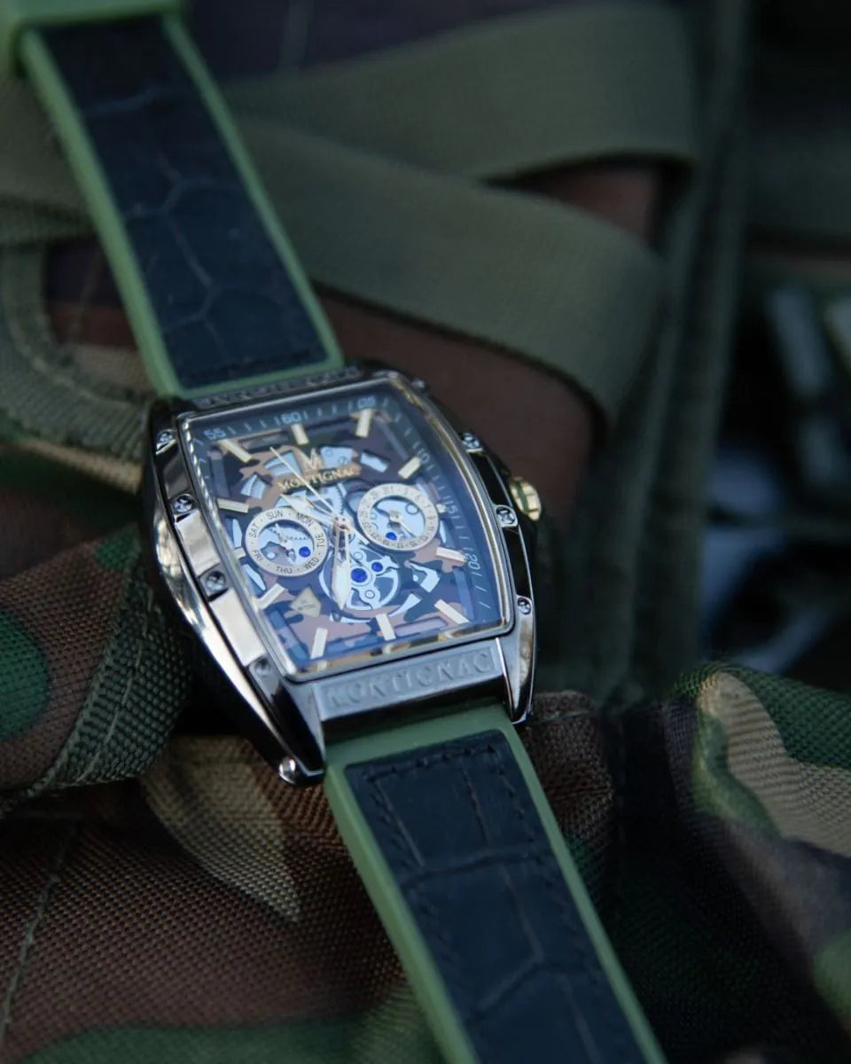 Luxury watch with a green strap worn on a wrist, blurred background