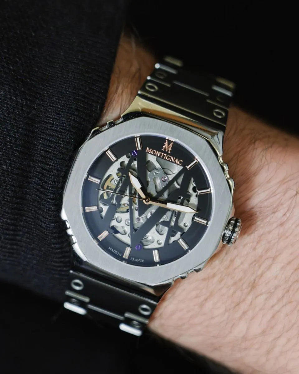 Luxury watch with visible brand name on a person's wrist against a dark background
