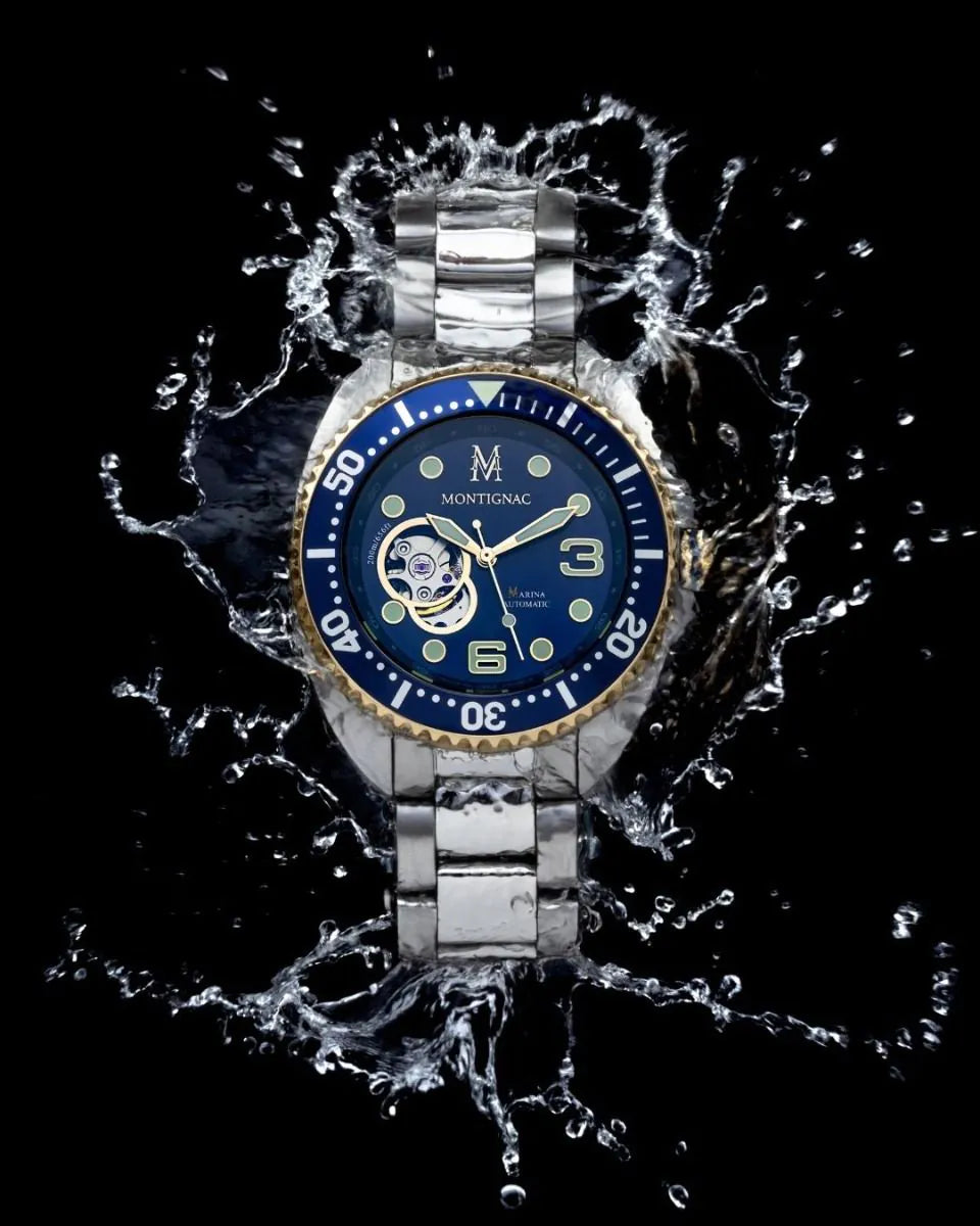 Silver watch with blue face surrounded by water splashes on a black background