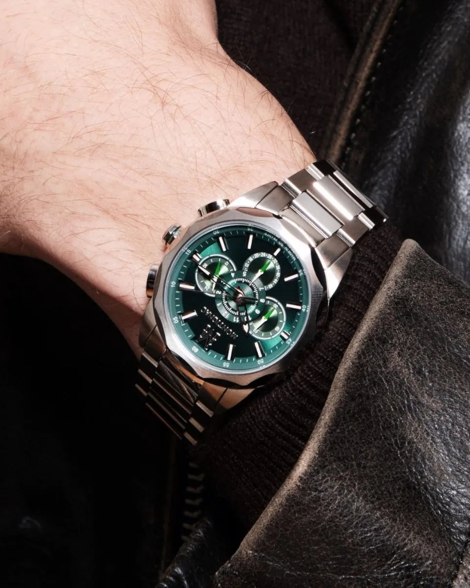 Close-up of a wrist wearing a silver watch with a green face.
salam Luxury UAE
