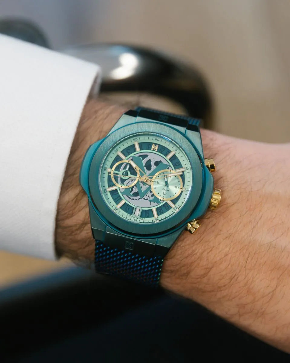 Green | Teal wristwatch with gold accents on a person's wrist against a blurred background
Salam Luxury UAE
