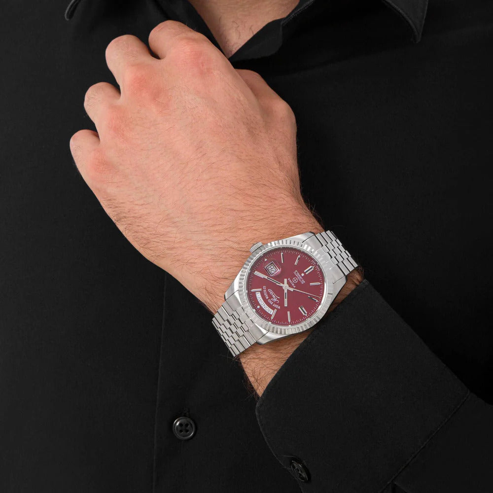Maroon | Close-up of a wrist wearing a silver watch with a red face against a black background
Salam Luxury UAE